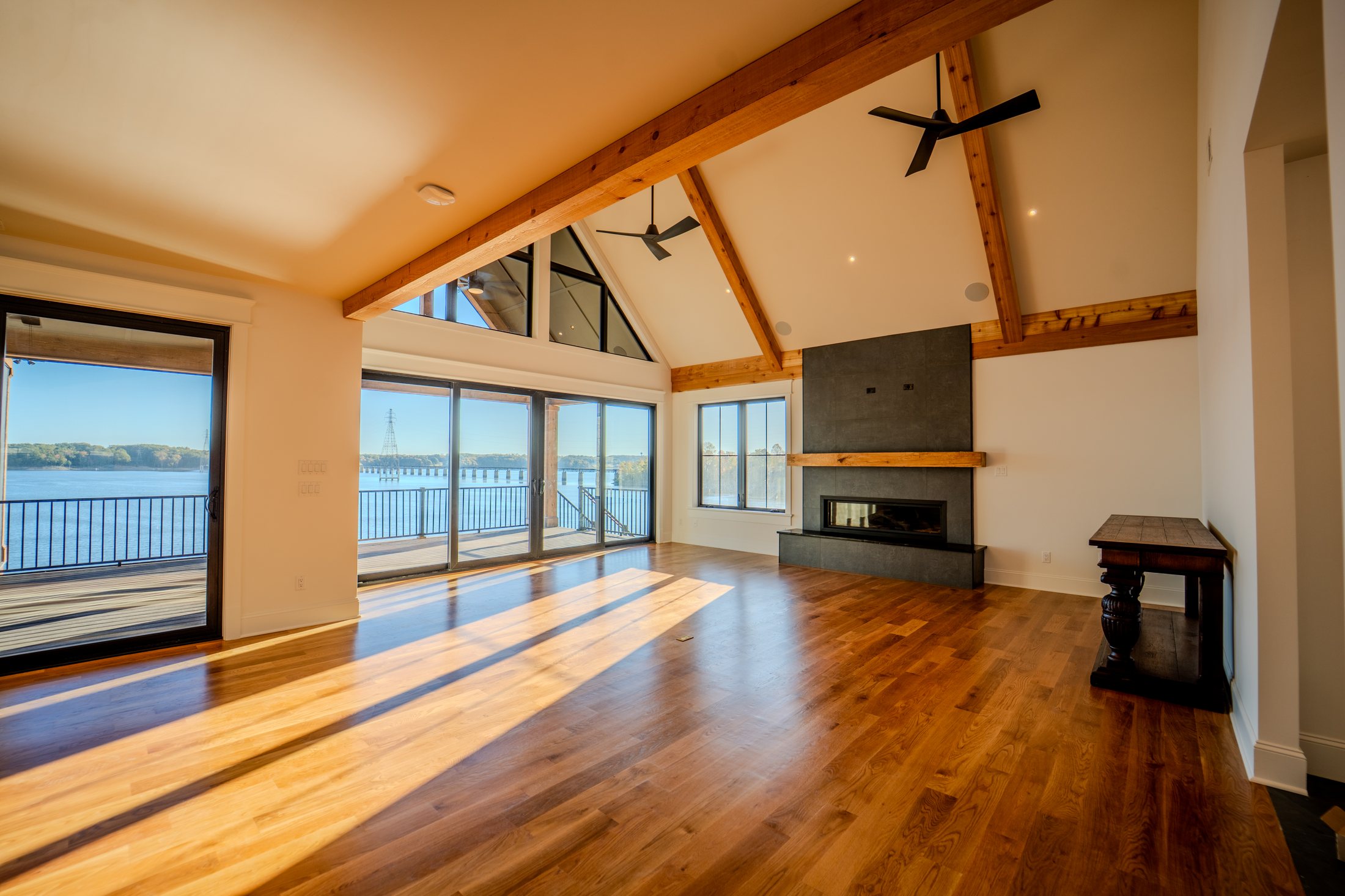 House on the lake great room with timber beams, fireplace, and lake view